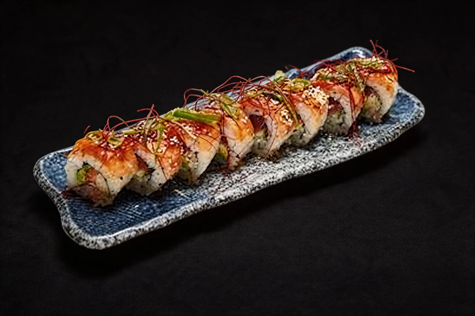 Signature saumon Roll on a long speckled blue plate, dark background.