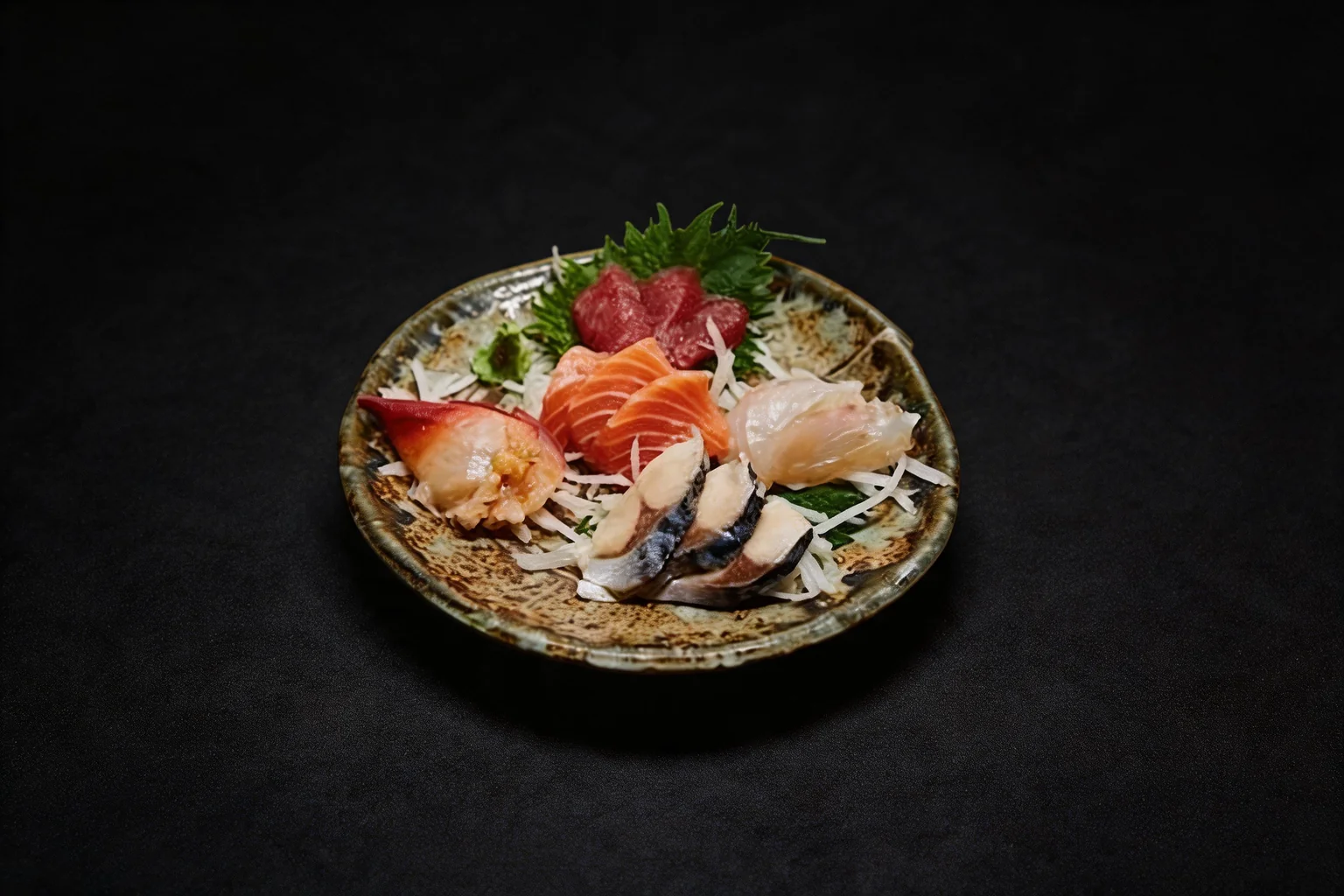 Sashimi set: sashimi on a round ceramic plate, dark background.