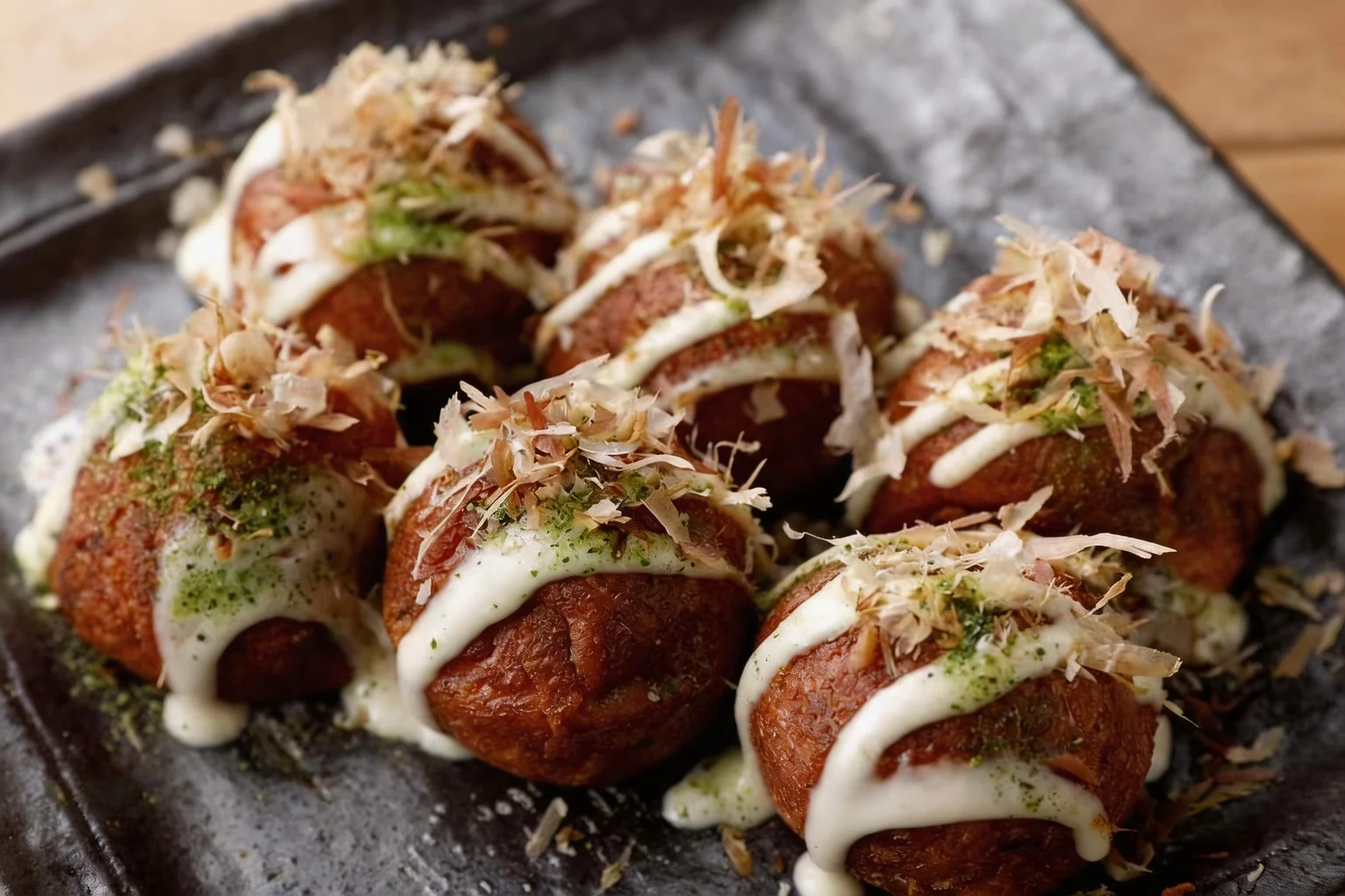 Takoyaki on a grey plate, wooden table.