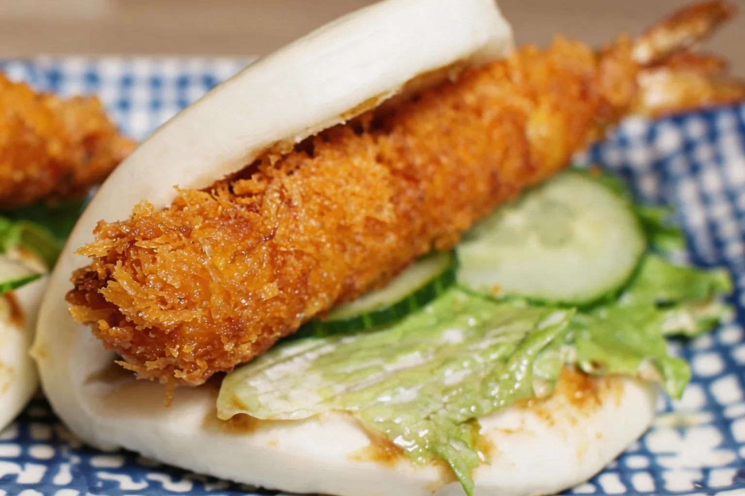 Shrimp fritter bao on a blue and white plate.